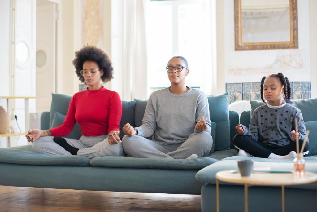 Mastering the First Impression: Your intriguing post title goes here A mother and daughters meditating on a couch, promoting relaxation and bonding time at home.