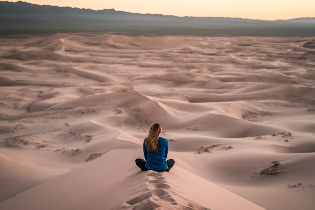woman-sitting-on-sand-field-yw1y-alkgrg